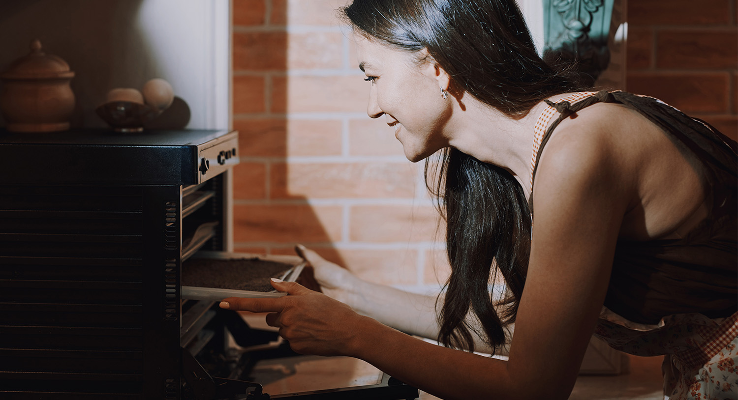 kobieta-uśmiechnięta-używa-piekarnika-suszy-suszenie-grzyb&oacute;w-w-piekarniku